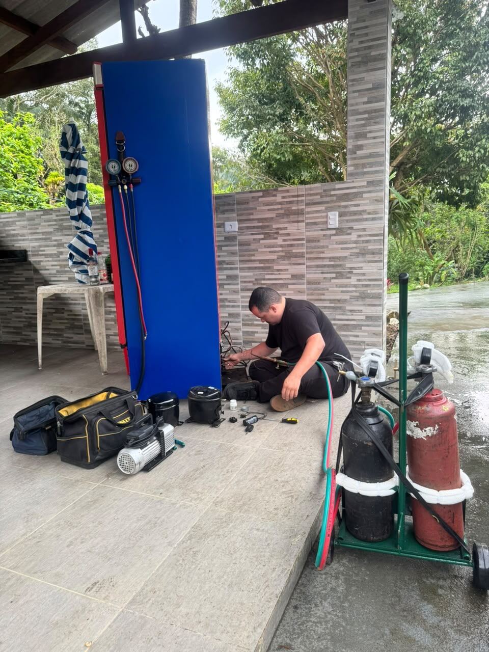 Técnico da ARTEC consertando uma geladeira com maçarico e manifold